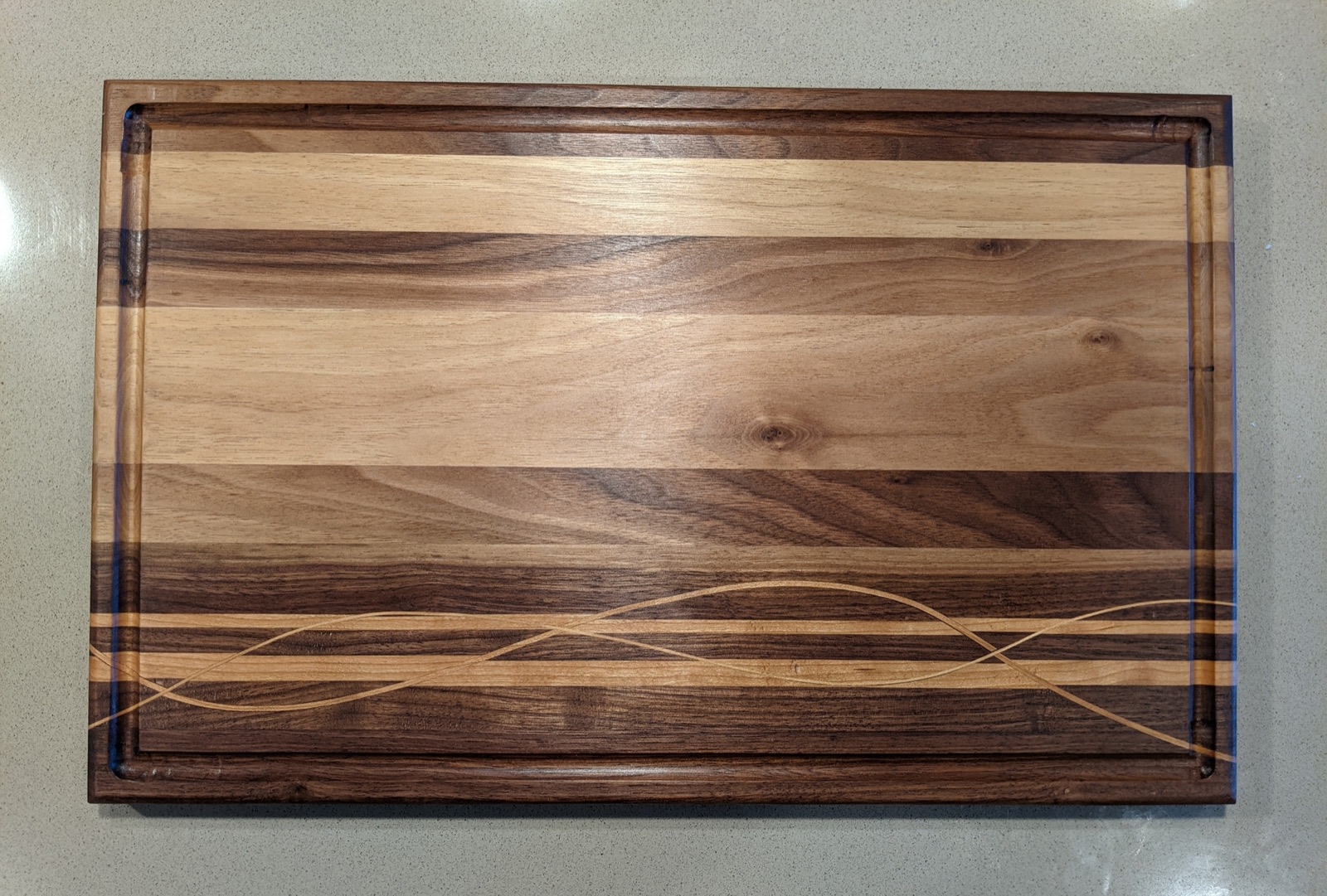 Finished walnut and cherry cutting board with ribbon detail and juice groove